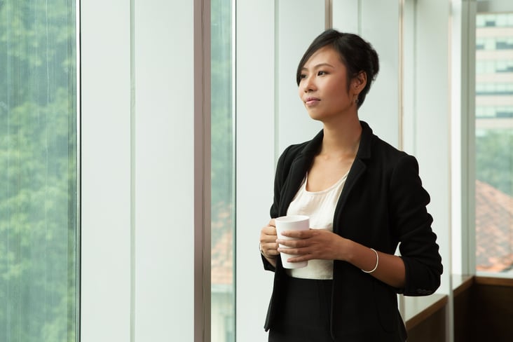 pensive businesswoman standing with coffee cup
