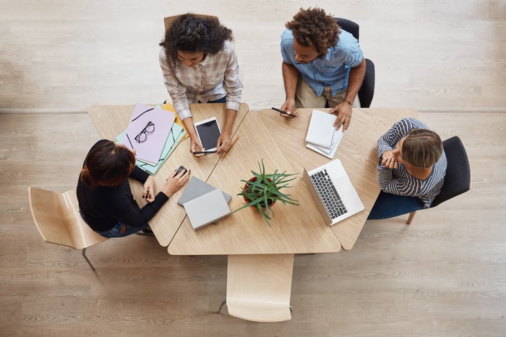 view-from-group-young-professional-entrepreneurs-sitting-table-coworking-space-discussing-profits-last-team-project-using-laptop-digital-tablet-smartphone